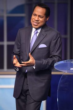 a man in a suit and tie standing at a podium with his hands out to the side