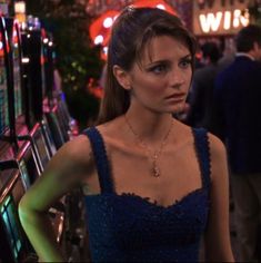 a woman in a blue dress standing next to a row of vending machine machines