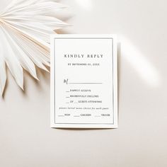 a white wedding card with a palm leaf next to it