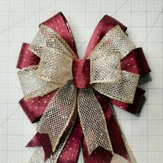 a red and gold bow on top of a cutting board next to a ruler with white dots