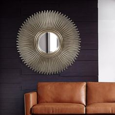 a living room with a brown leather couch and a round mirror on the wall above it