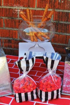 some snacks are sitting in bags on a red and white table cloth near a brick wall