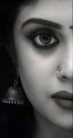 a close up of a woman with makeup on her face and nose piercing in the middle