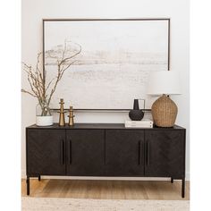 a living room with a large painting on the wall next to a black sideboard