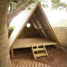 a wooden platform under a tree with a tent on it's side and stairs leading up to the top