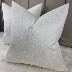 two white pillows sitting on top of a bed next to a headboard and pillow