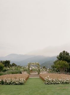 an outdoor ceremony set up with white flowers and greenery