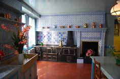 an old fashioned stove in the middle of a room with blue and white tiles on the walls