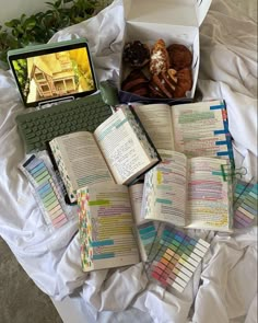 an open laptop computer sitting on top of a bed next to books and other items