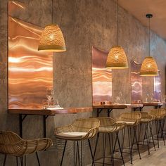 a long table with chairs and lights hanging from the ceiling in a restaurant or bar