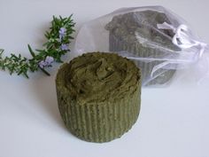 a cupcake with green frosting next to a plastic wrapper and small purple flowers