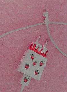 a white bag with strawberries on it is hooked up to a charger and cord