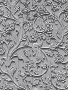 an intricately designed tile wall with white flowers and leaves on the tiles, as well as