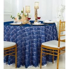 a blue table cloth with gold candles and flowers on it is set up for a formal dinner