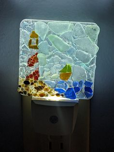 a light that is on top of a toilet paper dispenser with sea glass in it