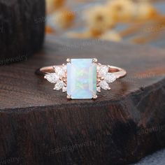 an opal and diamond ring on top of a wooden table