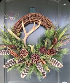 a wreath with antlers and pine cones hanging on a door