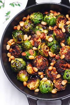 brussel sprouts and pine nuts in a skillet on a white surface