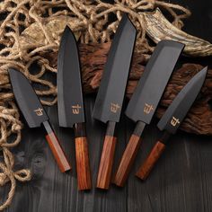 five knives sitting next to each other on top of a wooden table with rope and burl