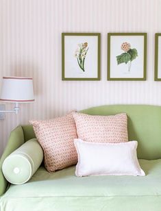 a green couch with pillows and pictures on the wall