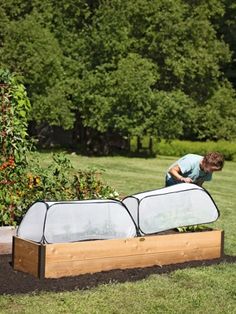 a man is working in the garden with his raised planter box and cover over it