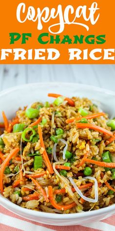 fried rice with carrots and green onions in a white bowl on top of a table