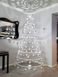 a white christmas tree is in the middle of a room with a mirror on the wall