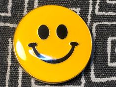 a yellow smiley face button sitting on top of a black and white cloth covered floor