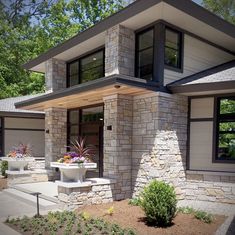 a modern house with two planters in the front yard