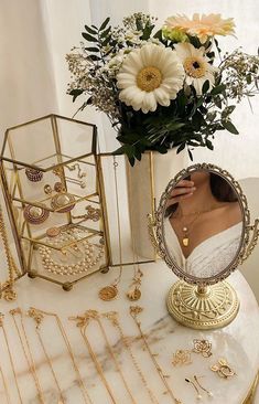 there is a vase with flowers and jewelry on the table next to an ornate mirror