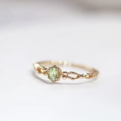 a gold ring with an oval shaped green stone in the center and two small diamonds on each side