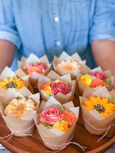 there are many small flowers in paper bags on the table and someone is holding them