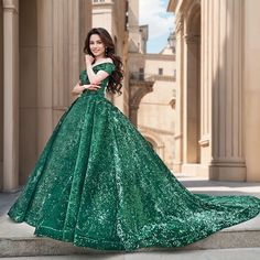 a beautiful woman in a green dress posing for the camera on steps outside an old building