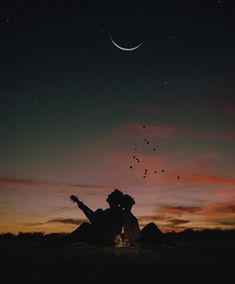 two people are sitting on the ground with their guitars in front of them at night