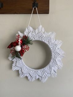 a white doily wreath hanging on a wall with red and white decorations around it