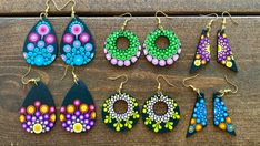 six pairs of colorful earrings are displayed on a wooden surface, with the word wow spelled out in large letters