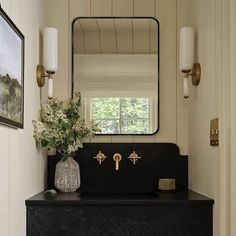 a bathroom with a sink, mirror and flowers on the counter top in front of it