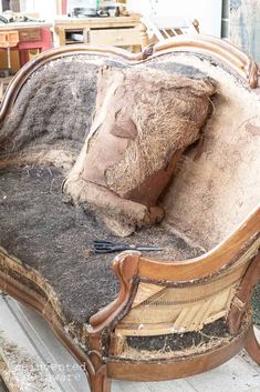 an old wooden chair with some dirt on it's back and seat cushion that has been turned into a couch