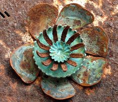 an old rusted metal flower on the ground