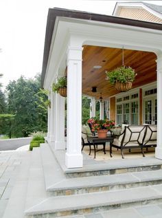 a porch with chairs, tables and potted plants