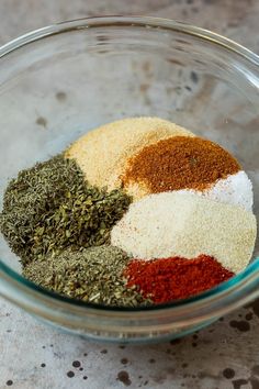 various spices in a glass bowl on top of a marble countertop, including red, white and green seasoning