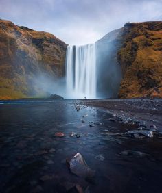 a large waterfall in the middle of a body of water with rocks on both sides