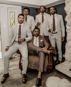 a group of men wearing suits and ties posing for a photo in a living room