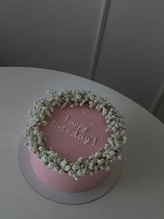 a pink birthday cake with white flowers in the shape of a heart that says happy birthday