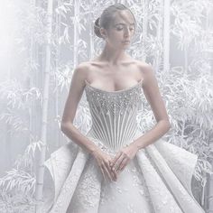 a woman in a white wedding dress standing in front of bamboo trees with her hands on her hips