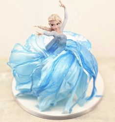 a frozen princess figurine sitting on top of a white cake covered in frosting