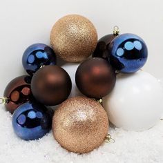 a group of christmas ornaments sitting on top of snow covered ground with white and blue balls