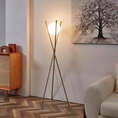 a living room scene with focus on the floor lamp and artwork hanging above the couch