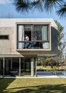 the house is made out of concrete and has large windows