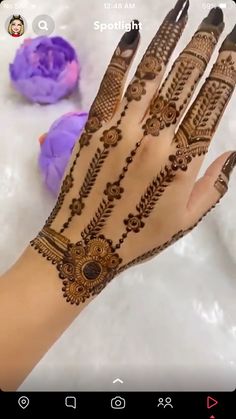 a woman's hand with henna on it and some flowers in the background